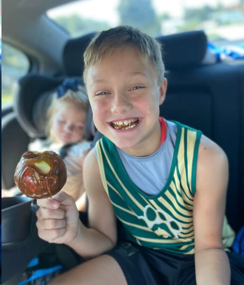 A young attendee enjoying a caramel apple at a Cave Lake community event