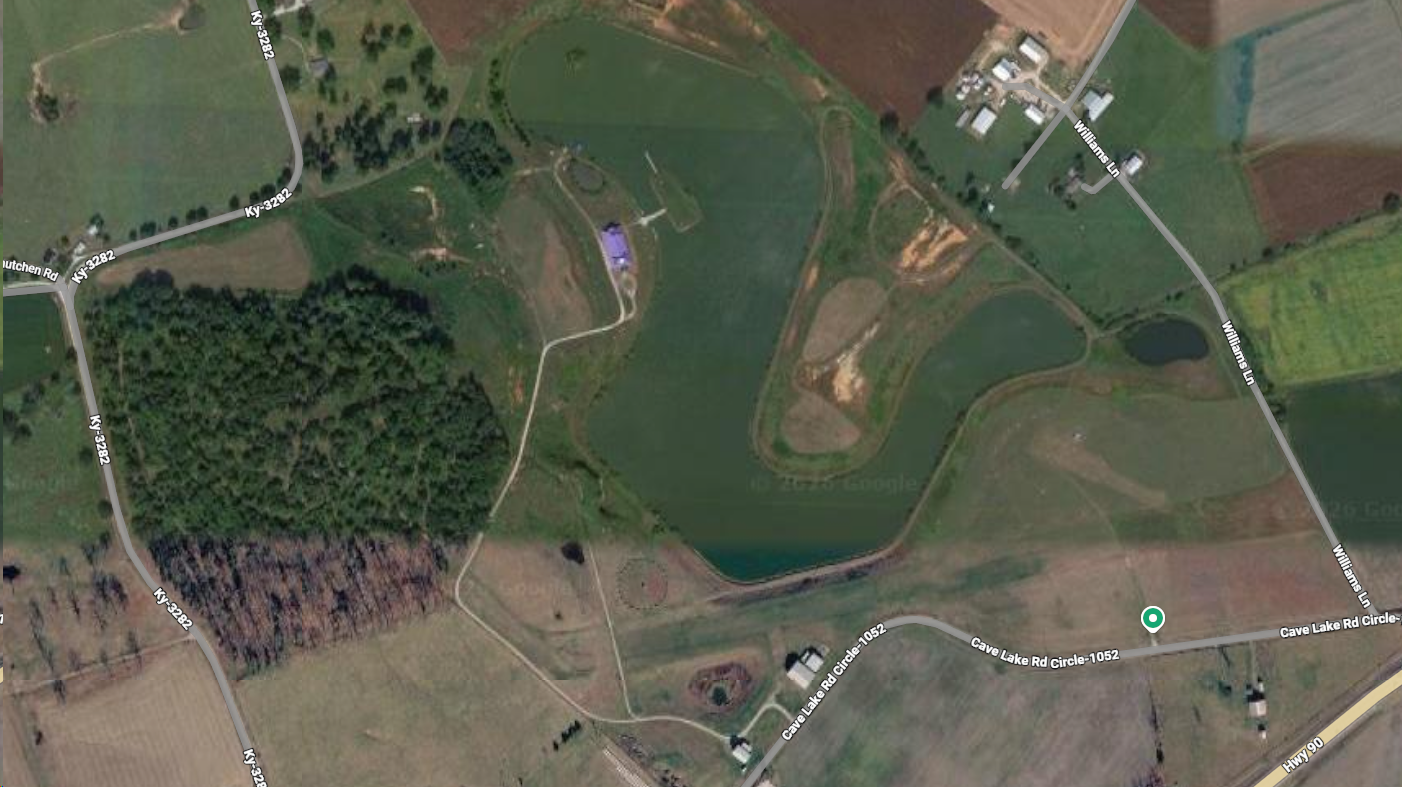 Aerial view of Cave Lake Event Park showing the lake, event hall, surrounding woods, and farmland in Monticello, Kentucky